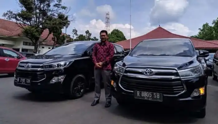 Driver BAG Transport kemeja batik kustom dengan armada Sewa Innova Reborn hitam yang bersih dan elegan