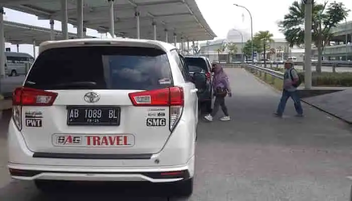 Tampak belakang mobil Innova BAG Travel putih dengan branding jelas dan plat nomor, rute via Wonosobo.